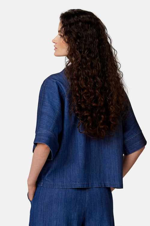 Blouse en jean bleu clair de COPINES D'ANVERS, coupe décontractée, manches larges retroussées, vue de dos.