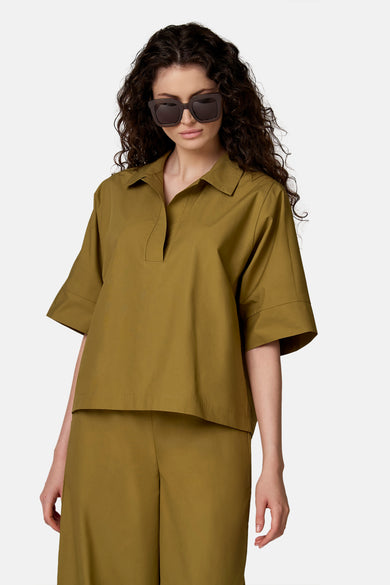 Kaki groen blouse van COPINES D'ANVERS met korte mouwen en een losse pasvorm, van opzij gedragen met een bijpassende broek en een zonnebril.