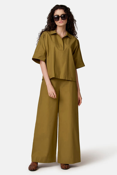 Groen blouse met korte mouwen van COPINES D'ANVERS, losse pasvorm en polokraag, gedragen met een bijpassende broek en loafers.