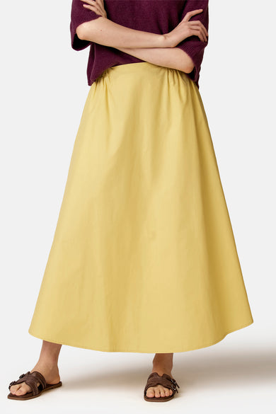 Jupe jaune de COPINES D'ANVERS, longue et évasée avec taille élastiquée, portée avec un pull bordeaux et des sandales marron.