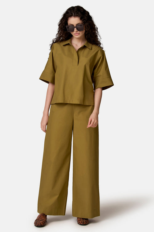 Groene broek met wijde pasvorm van COPINES D'ANVERS, gedragen met een bijpassend topje en loafers met slangenprint.