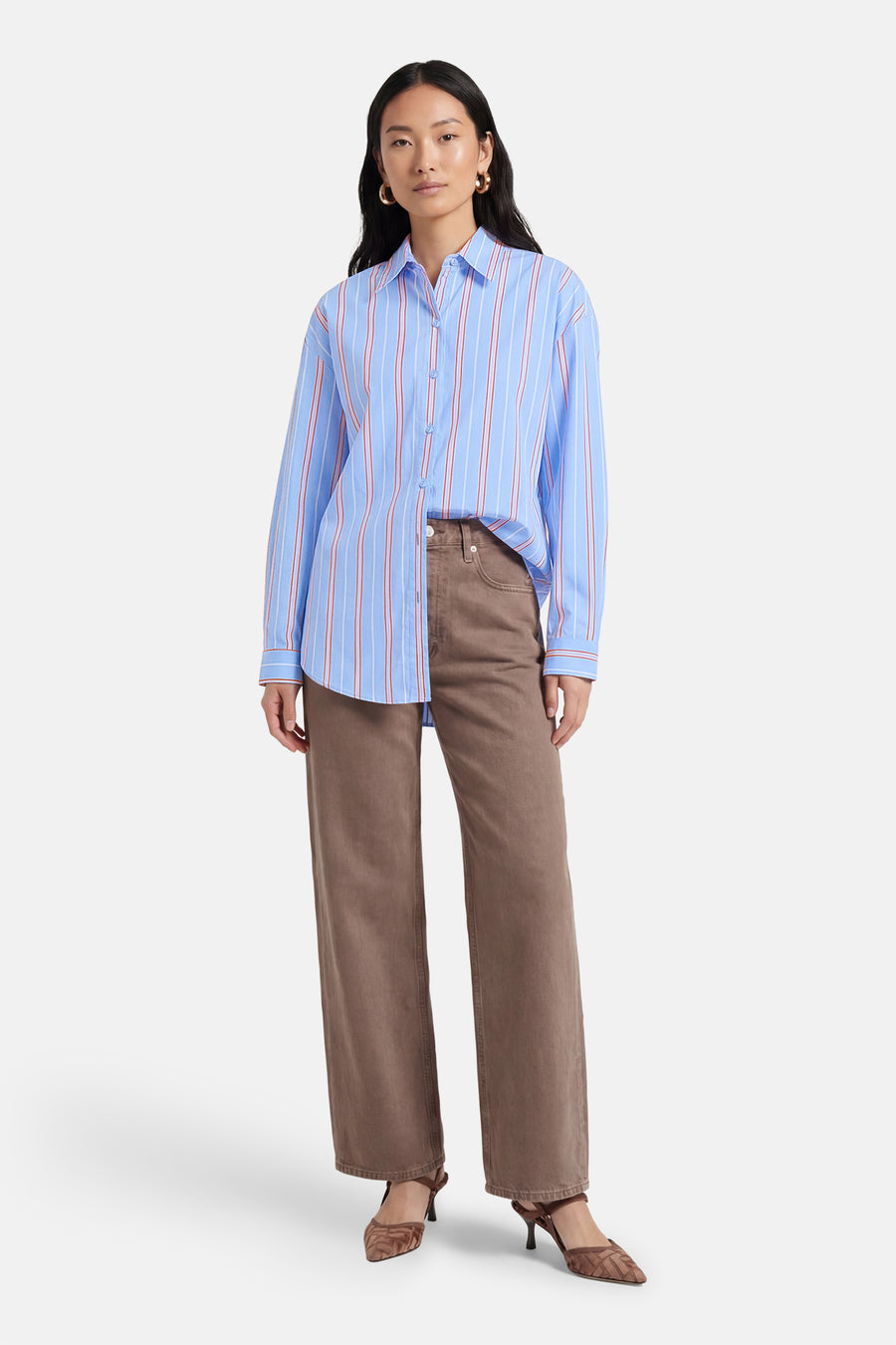 Chemise à manches longues multicolore d'AMELIE ET AMELIE avec des rayures bleues, rouges et blanches, portée avec un pantalon marron et des talons.
