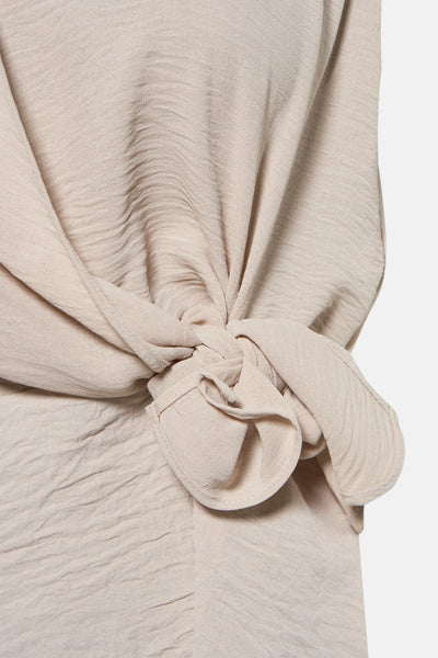 Blouse beige à manches courtes de NAF NAF, avec un nœud décoratif texturé.