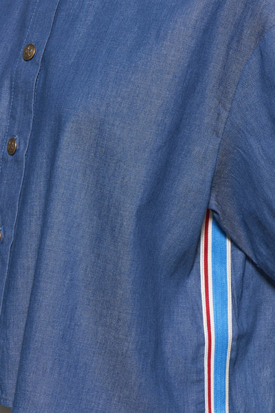 Blouse en denim bleu moyen de NAF NAF avec rayures décoratives bleues, blanches et rouges.

