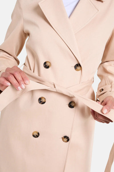 Veste longue beige de NAF NAF avec ceinture assortie et boutons marron.