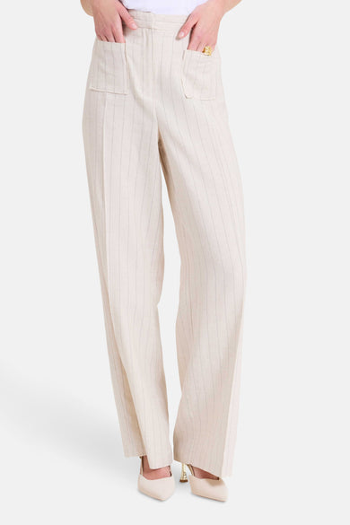 Pantalon beige à rayures verticales de NAF NAF, avec poches plaquées et chaussures pointues assorties.

