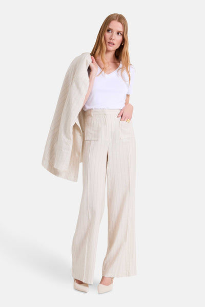Pantalon beige à rayures fines par NAF NAF, avec poches plaquées et porté avec un t-shirt blanc.

