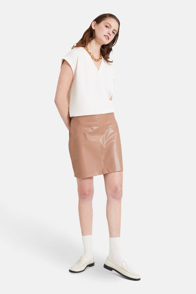 Ecru T-shirt met korte mouwen van NAF NAF, gedragen met een leren rok en loafers.