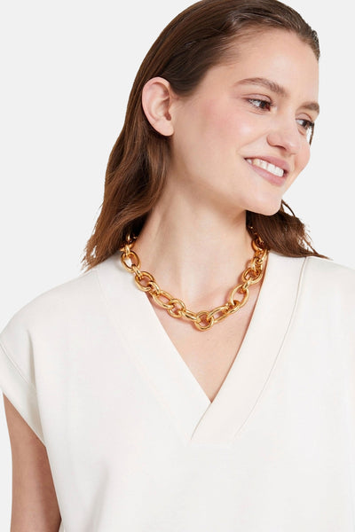 Ecru T-shirt met korte mouwen van NAF NAF, gedragen met een gouden ketting met grote schakels.
