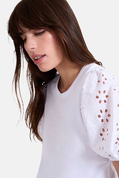 Blouse blanche à manches courtes de NAF NAF, avec détail brodé fleuri aux manches ballon.
