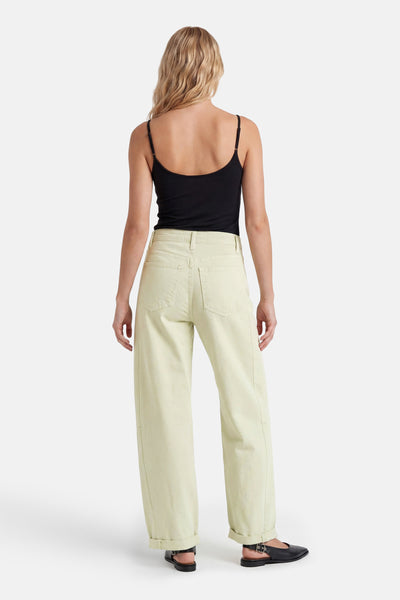 Light green high-waisted wide-leg five-pocket trousers back view with cuffed hems and black top and shoes