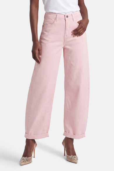 Rose pink wide-leg five-pocket women's pants with cuffed hems, worn with white top and embellished heels, front view