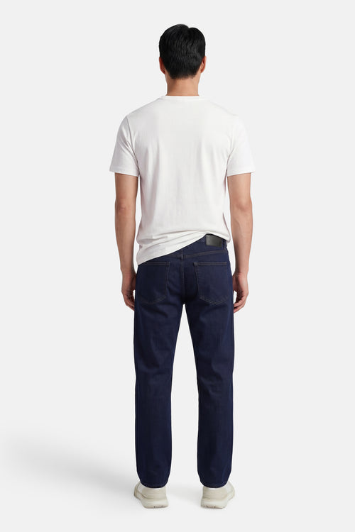 T-shirt écru de STROM, porté de dos par un homme avec un jean bleu foncé et des baskets claires.
