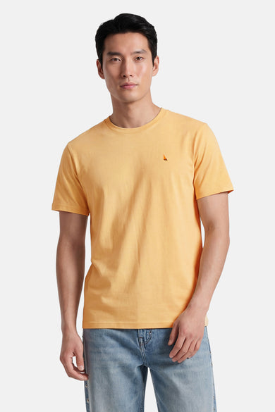 T-shirt jaune de STROM avec un petit logo voilier sur la poitrine, porté par un homme en jean délavé.