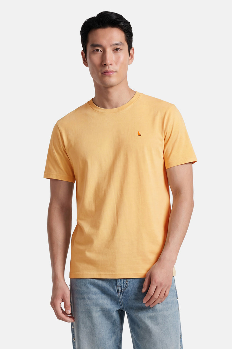 T-shirt jaune de STROM avec un petit logo voilier sur la poitrine, porté par un homme en jean délavé.