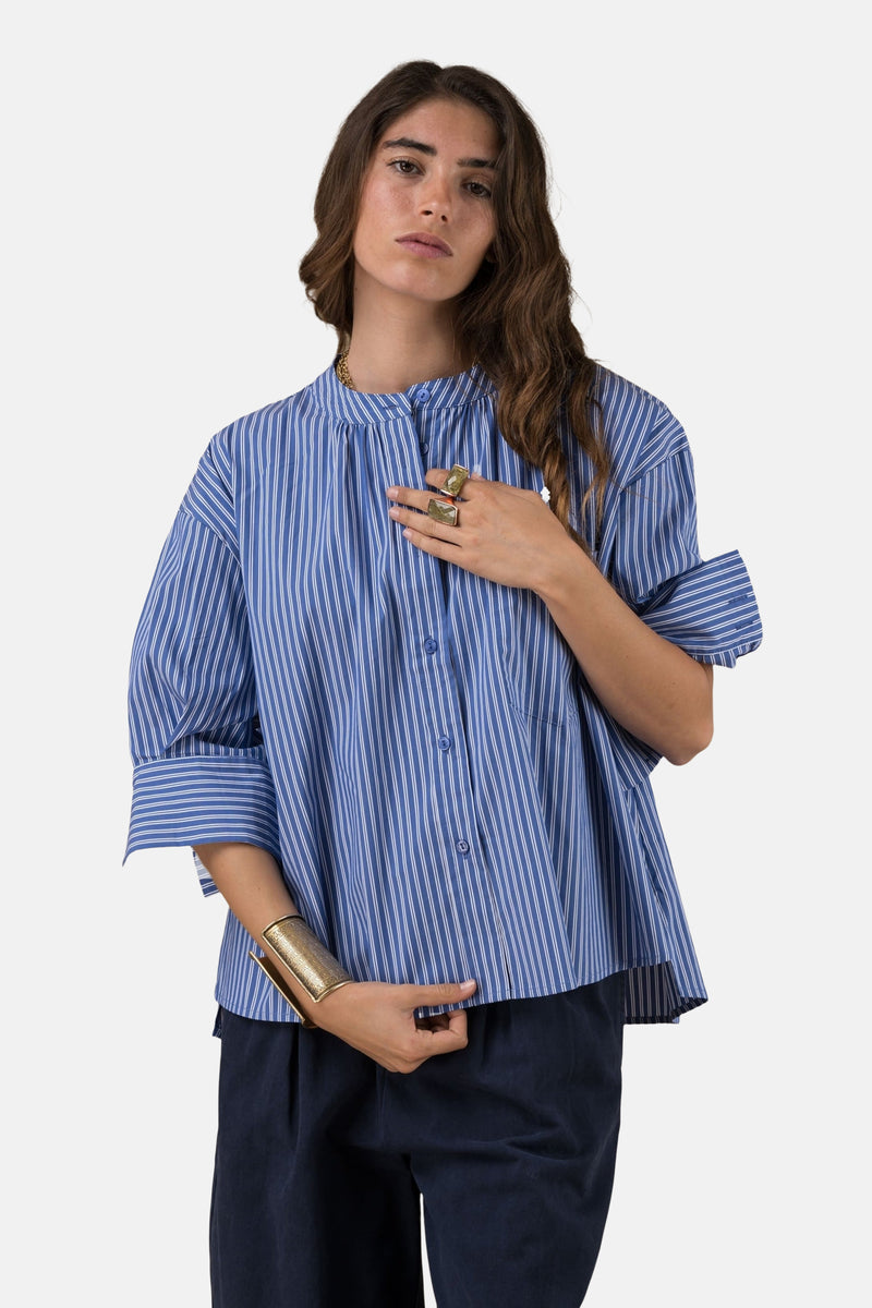 Blauwe gestreepte blouse met lange mouwen van ADORE, gedragen met een donkere broek en gouden sieraden.