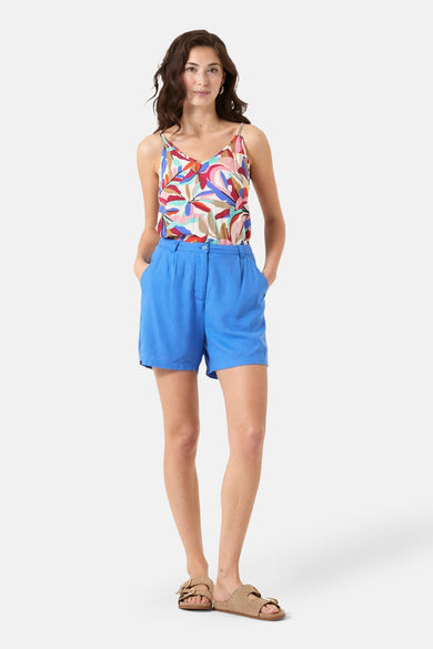 Multikleurig topje met spaghettibandjes van GARCIA, bloemenprint en gedragen met een blauwe short.