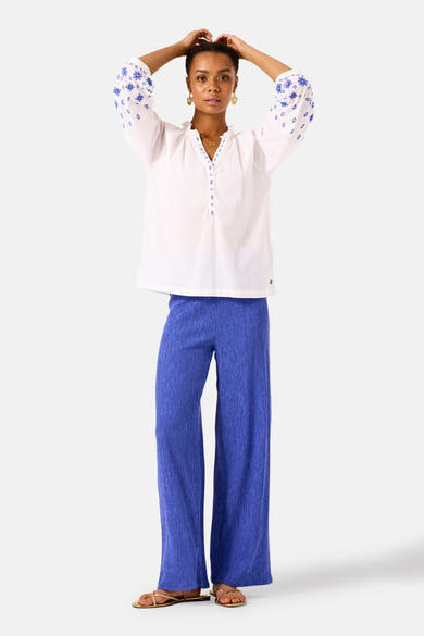 Pantalon bleu texturé de GARCIA, coupe ample avec une texture plissée et souple, porté avec un chemisier blanc brodé.
