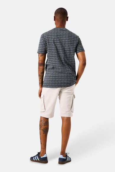 T-shirt à manches courtes kaki GARCIA, à rayures horizontales, porté avec un short cargo beige et des chaussures de sport bleues.