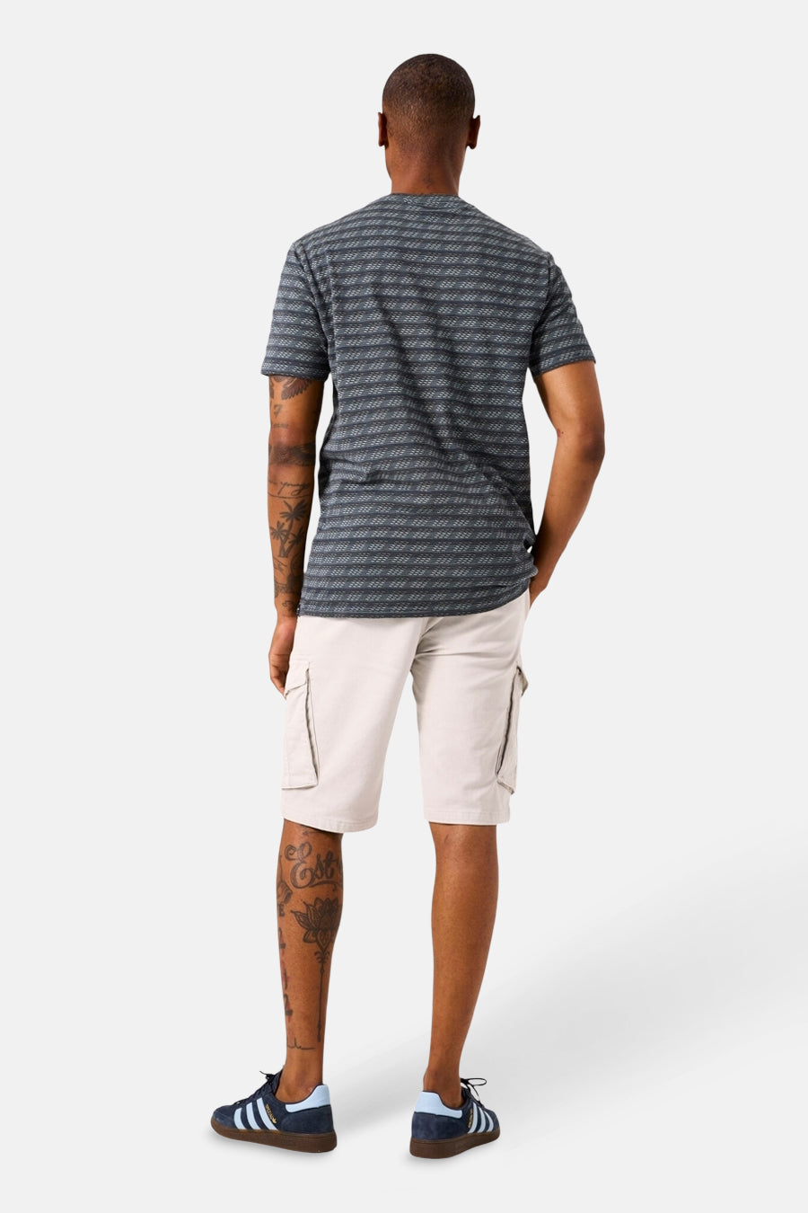 T-shirt à manches courtes kaki GARCIA, à rayures horizontales, porté avec un short cargo beige et des chaussures de sport bleues.