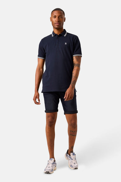 Blauw poloshirt met korte mouwen van GARCIA, met witte strepen op de kraag en mouwen, gedragen met een donkere spijkerbroek.
