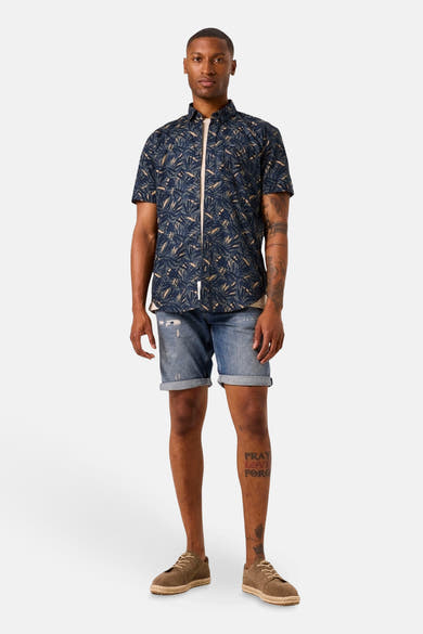 Chemise à manches courtes bleue à motif, par GARCIA, portée avec un short en jean et des espadrilles marron.