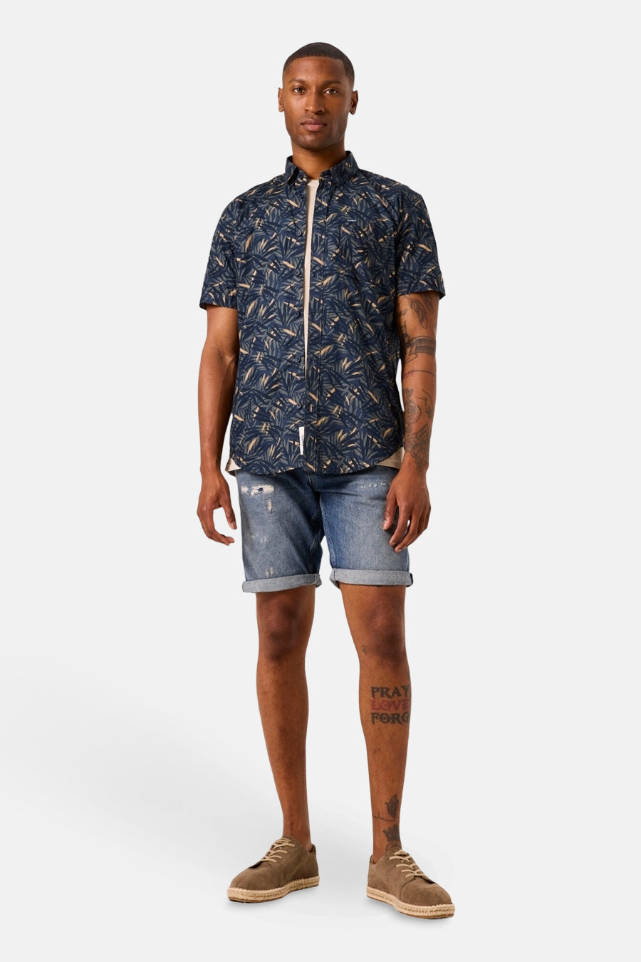 Chemise à manches courtes bleue à motif, par GARCIA, portée avec un short en jean et des espadrilles marron.