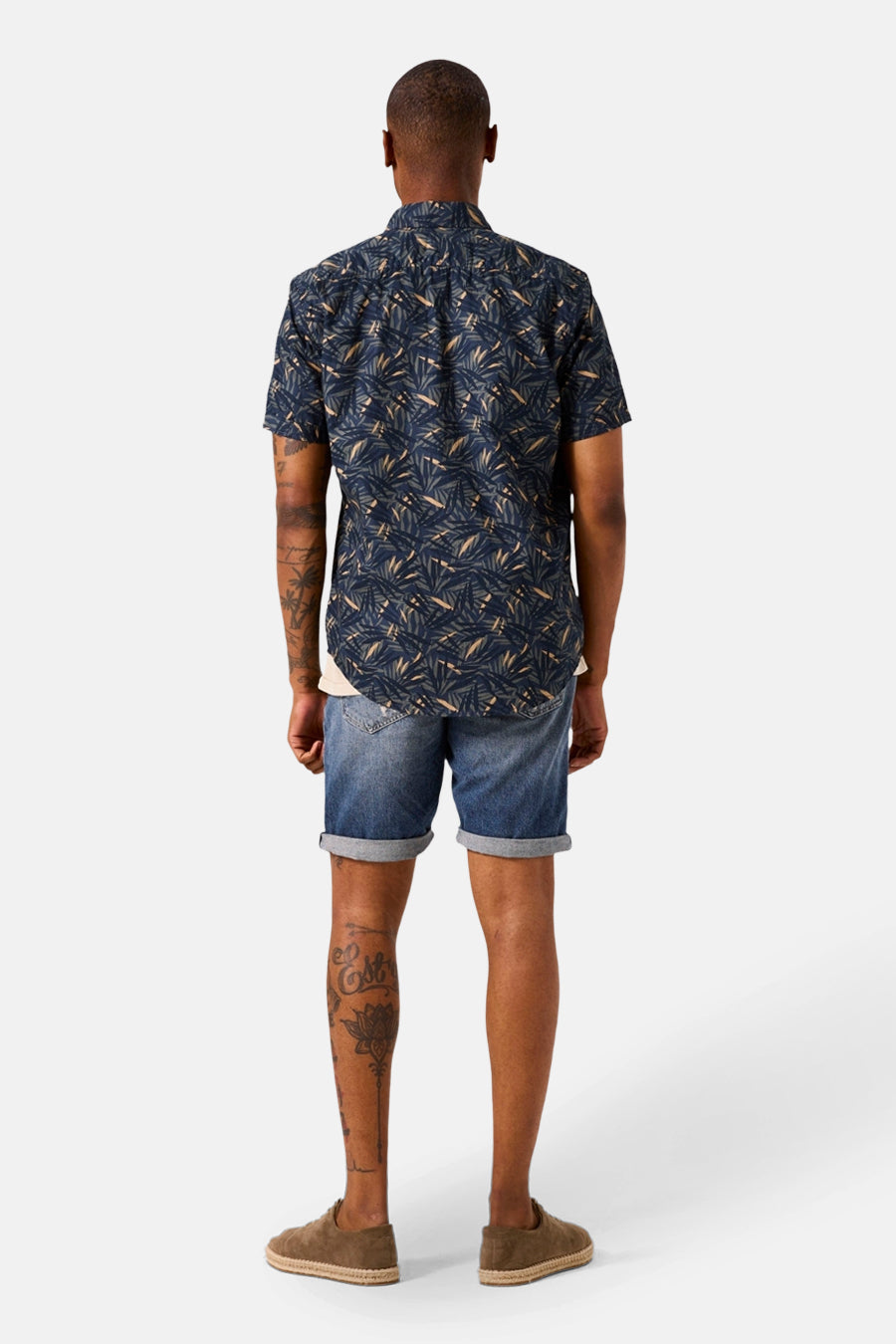 Chemise bleue à manches courtes de GARCIA, imprimé feuilles sur le dos, portée avec un short en jean.