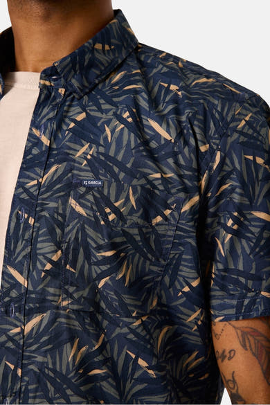 Chemise à manches courtes bleue à motif de feuilles par GARCIA, avec poche poitrine et manches courtes, portée sur un t-shirt clair.