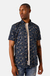 Chemise à manches courtes bleue à motif de feuilles par GARCIA, portée sur un t-shirt écru et un jean déchiré.