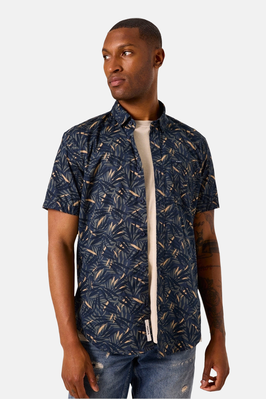 Chemise à manches courtes bleue à motif de feuilles par GARCIA, portée sur un t-shirt écru et un jean déchiré.
