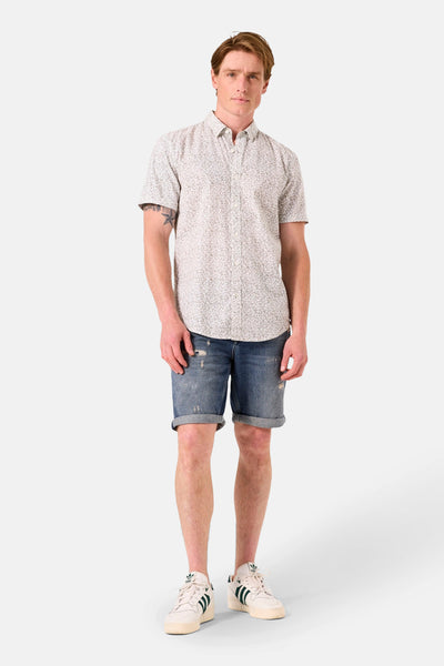 Chemise à manches courtes verte GARCIA avec un motif floral et portée avec un short en jean.