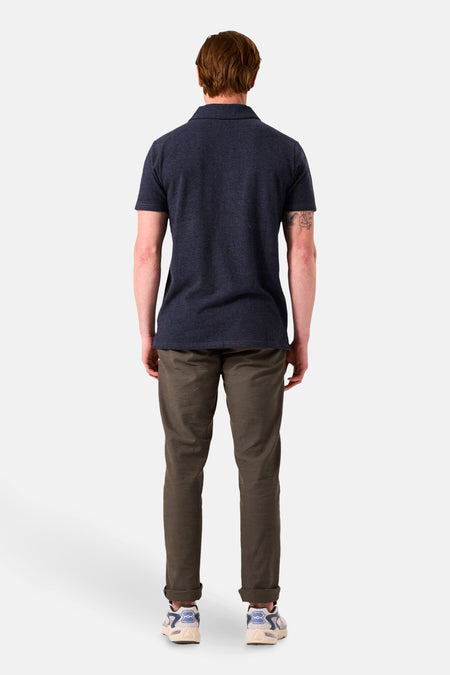 Kaki chino van GARCIA, gedragen met een marineblauw poloshirt en sneakers, van achteren gezien.