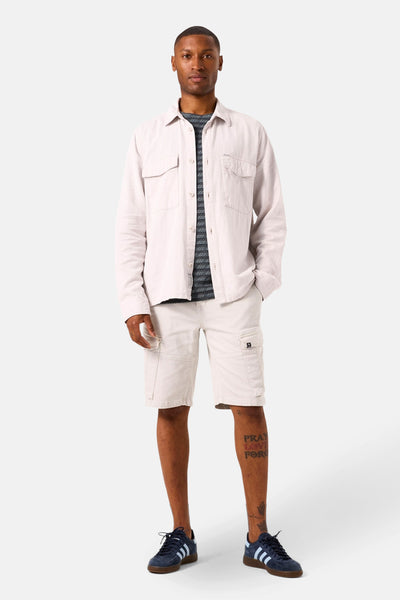 Bermuda gris GARCIA, avec poches cargo, porté avec une chemise écrue et des chaussures de sport bleues.