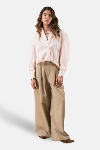 Roze overhemd met lange mouwen, van ADORE, met een beige wijde broek, gouden sieraden en bruine schoenen.