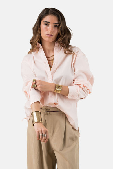 Roze overhemd met lange mouwen van ADORE, gedragen met gouden sieraden en een beige broek met hoge taille.