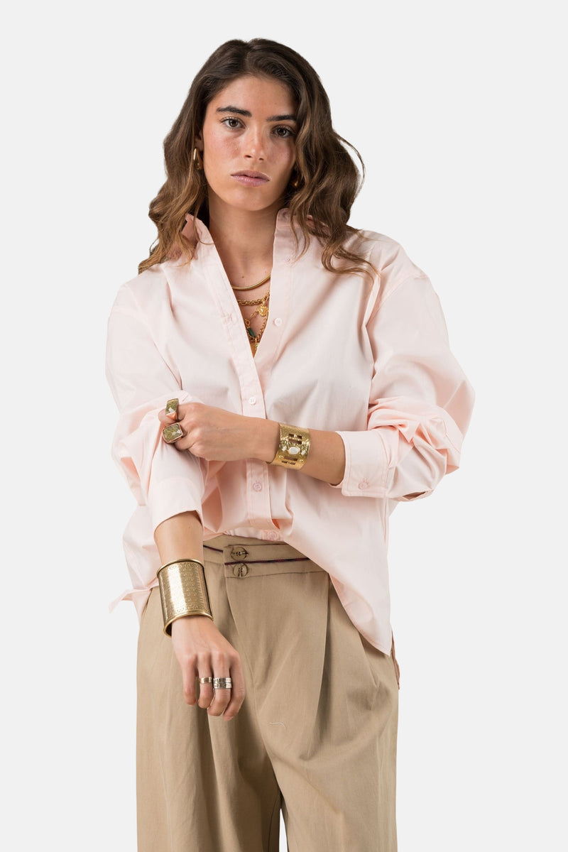 Roze overhemd met lange mouwen van ADORE, gedragen met gouden sieraden en een beige broek met hoge taille.