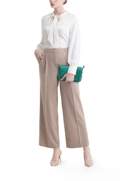 Sac à bandoulière vert texturé de PAUL MARIUS, tenu par une femme en blouse blanche et pantalon beige.