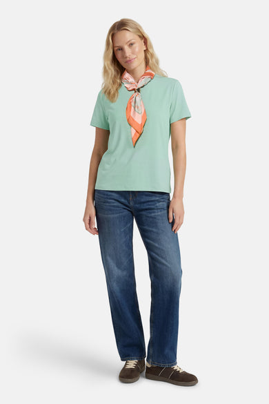 Green short-sleeve t-shirt with ribbed texture, worn with floral scarf and blue jeans, full-body front view
