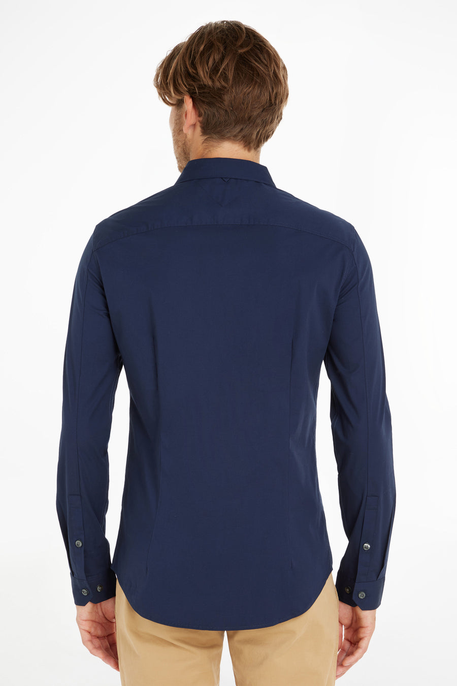 Chemise bleue à manches longues de Tommy Jeans, vue de dos, portée avec un pantalon beige.
