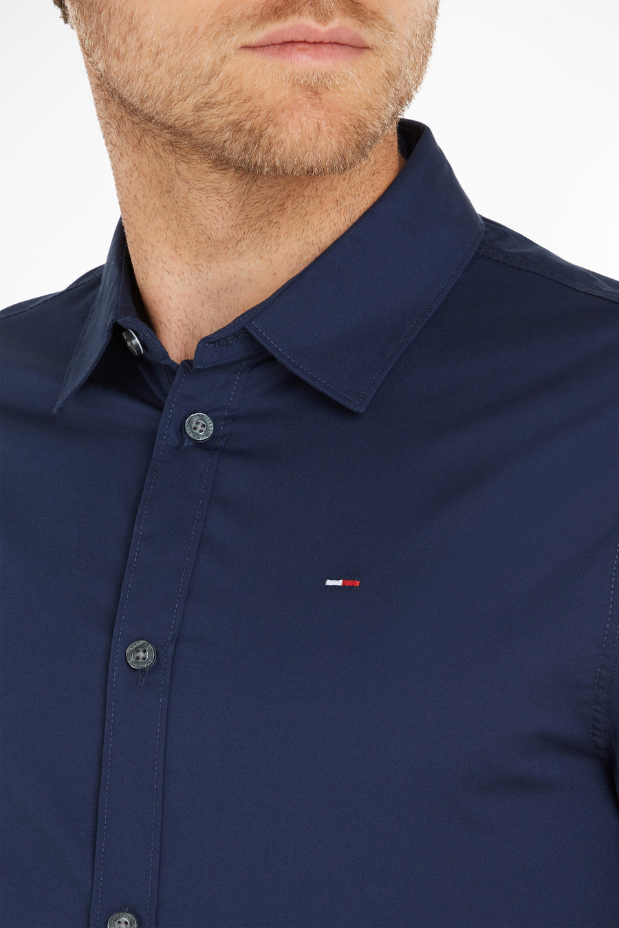 Chemise à manches longues bleue de Tommy Jeans, avec boutons apparents et logo discret sur la poitrine.
