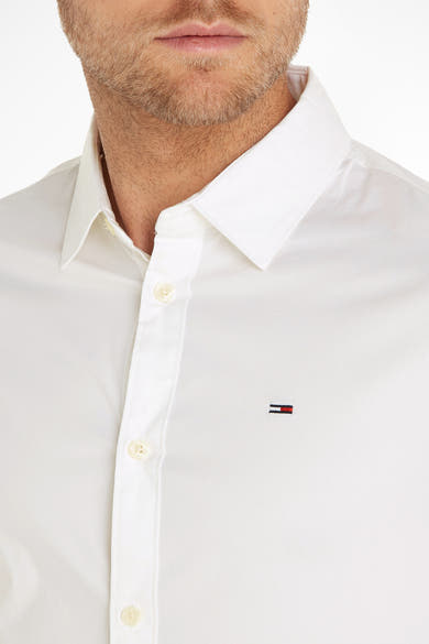 Chemise blanche à manches longues de Tommy Jeans, avec logo brodé et col classique.
