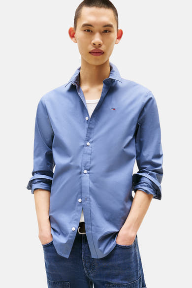 Blauw overhemd met lange mouwen van TOMMY JEANS, gedragen met een spijkerbroek met cargozakken en witte sneakers, van achteren gezien.