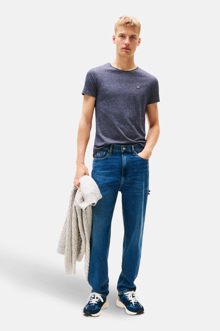 T-shirt bleu à manches courtes de Tommy Jeans, porté avec un jean bleu et des baskets.
