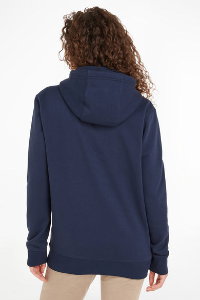 Sweat à capuche bleu marine de Tommy Jeans, avec une capuche, porté avec un pantalon beige, vue de dos.
