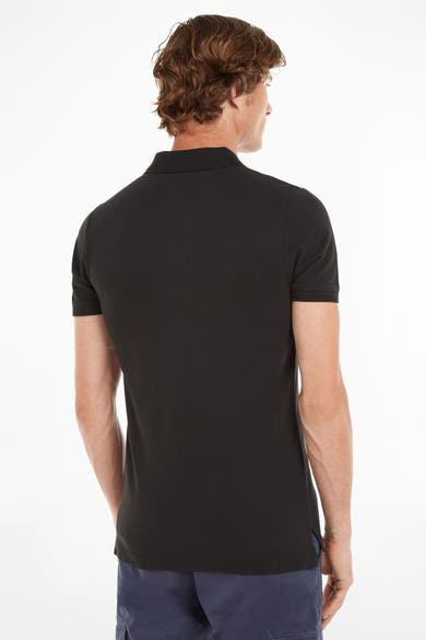 Polo noir de Tommy Jeans, vu de dos, porté avec un pantalon cargo bleu marine.
