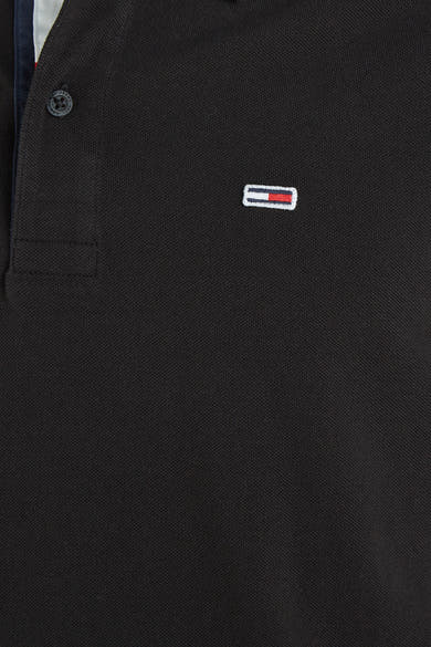 Polo noir de Tommy Jeans avec une texture piquée et logo distinctif.