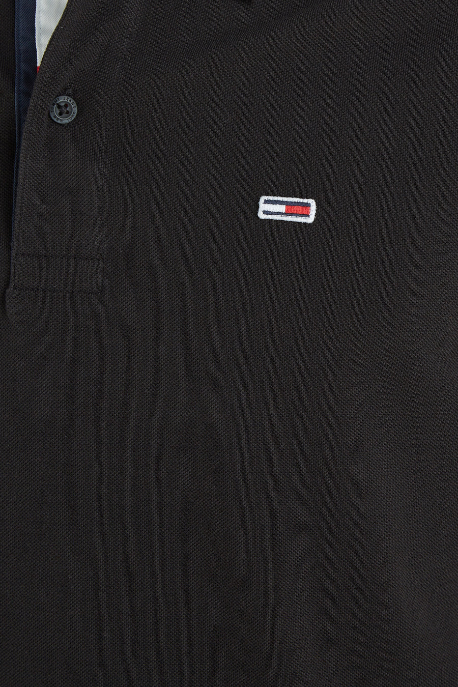 Polo noir de Tommy Jeans avec une texture piquée et logo distinctif.