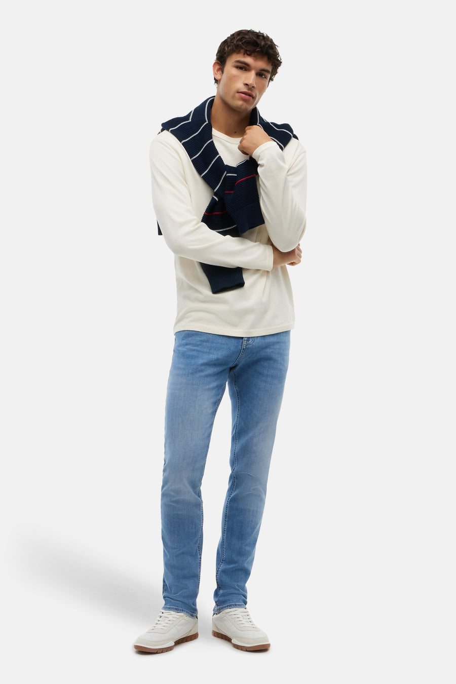 Light blue slim-fit denim jeans by TOMMY JEANS, worn with white long-sleeve tee and navy striped sweater, full-length front view