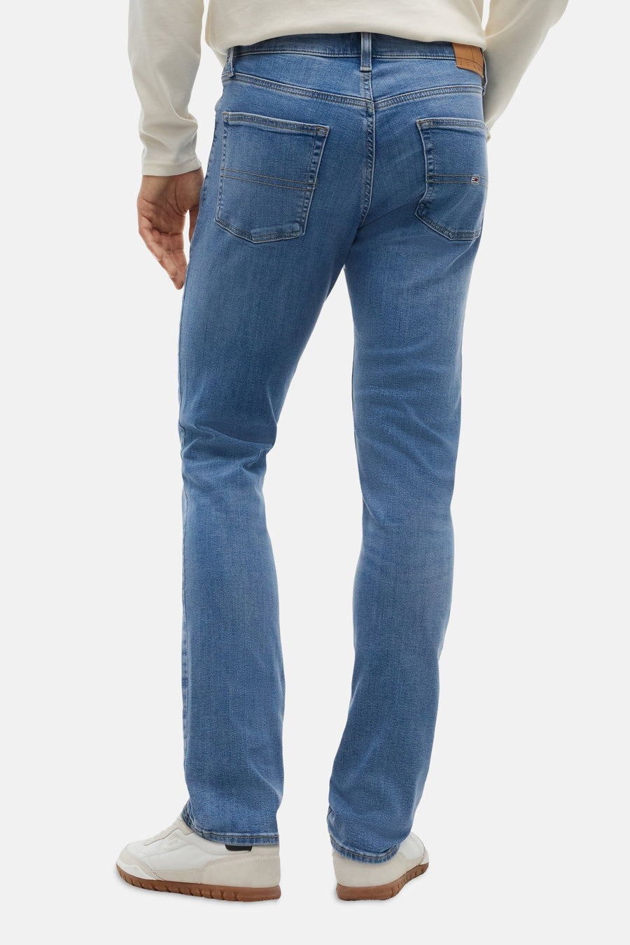 Light blue slim-fit denim jeans by TOMMY JEANS, back view showing clean stitching, two rear pockets with branded tab, and straight leg cut.